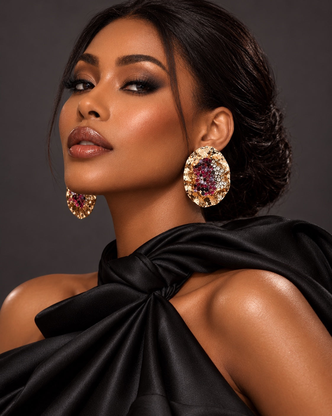 Woman wearing large gold hammered rhinestone statement stud earrings with pink multicolour crystal detail. Fatisha Boutique